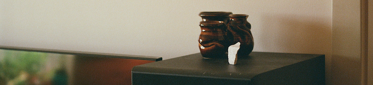 3 small ceramic vases and a chunk of white rock on top of a speaker